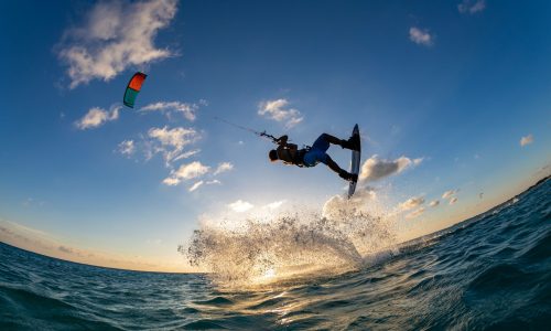 A person surfing and flying a parachute at the same time in Kitesurfing. Bonaire, Caribbean