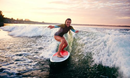 Young woman surfboarding at summer resort